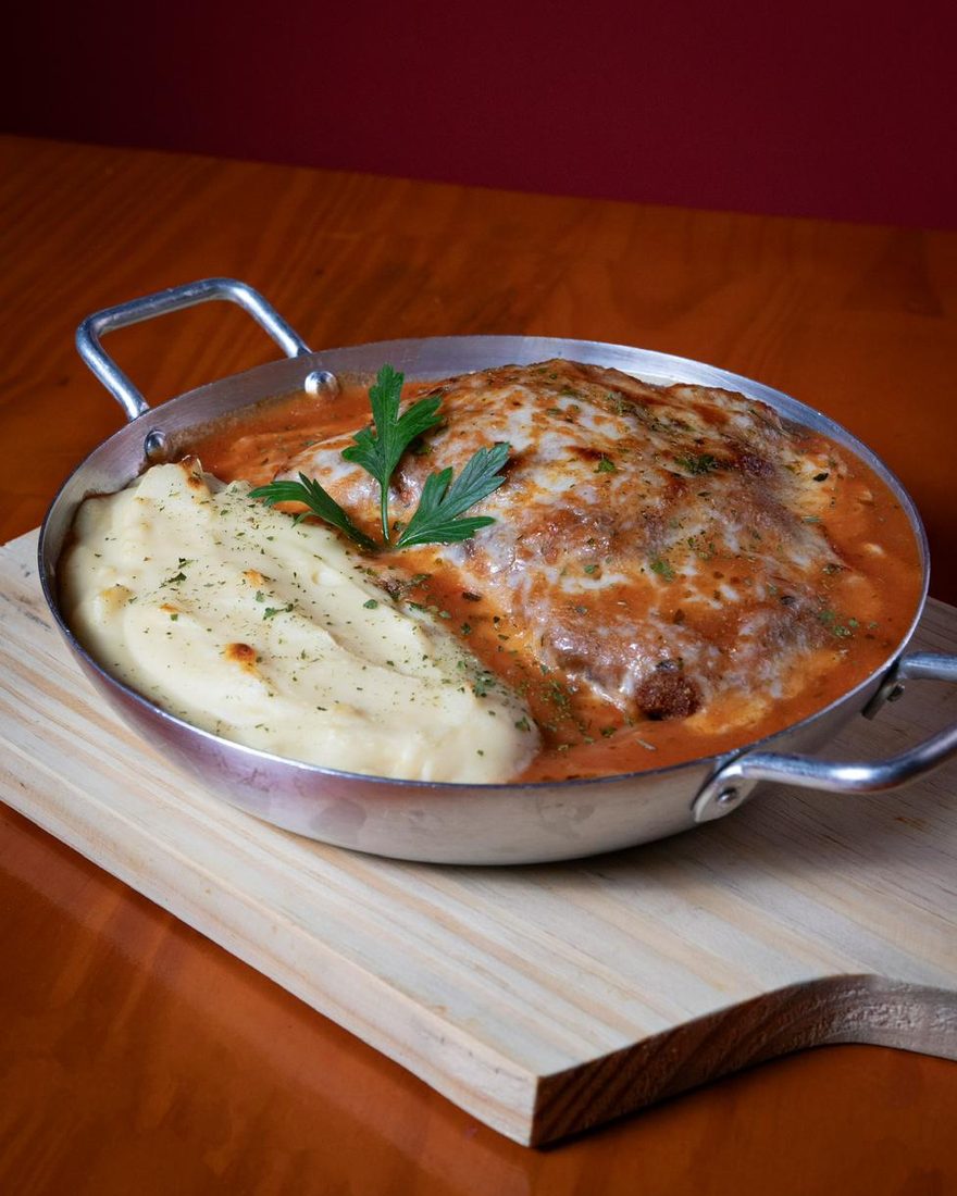 Filé à parmegiana na frigideira, com purê de batata ao lado e salsinha por cima