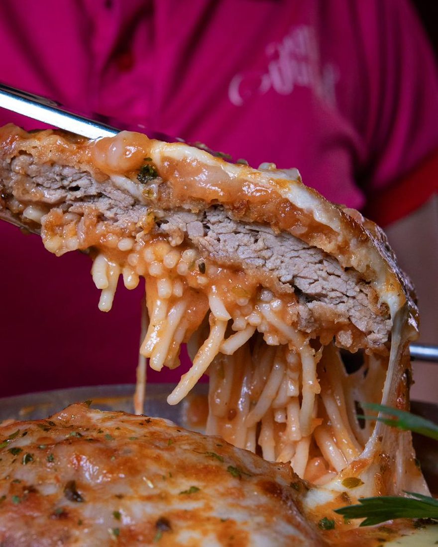 Fatia do filé à parmegiana em close, mostrando a carne, a crosta e o queijo derretido