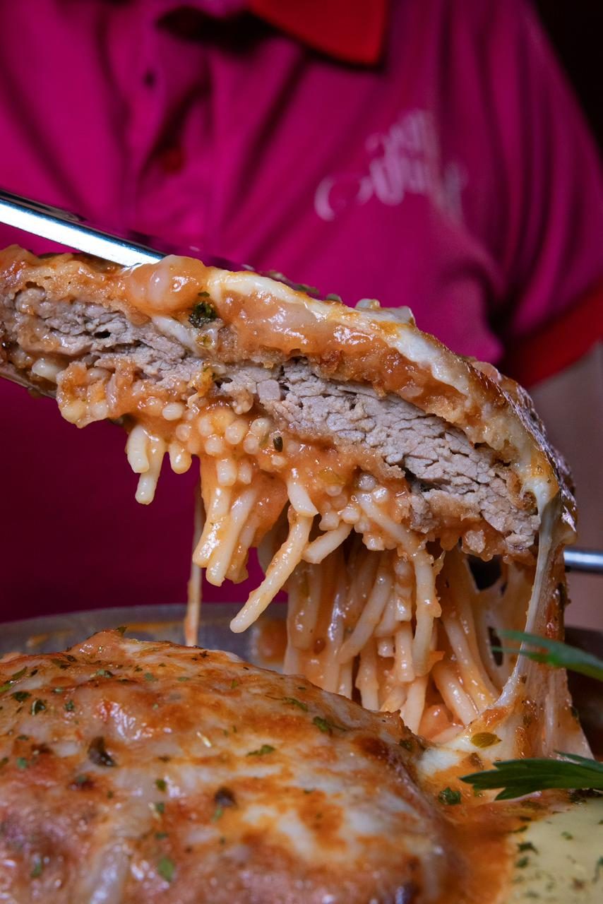 Garfada de filé à parmegiana com o espaguete e a mussarela puxando